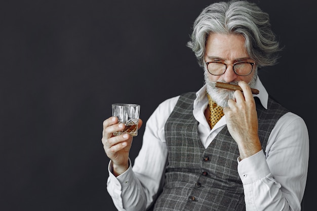 Close up portrait of grinning old-fashioned man.  Grandfather with a cigar and whiskey.