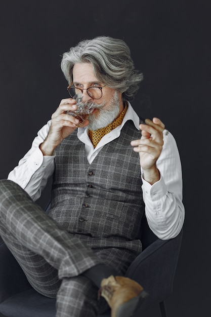 Close up portrait of grinning old-fashioned man.  Grandfather with a cigar and whiskey.