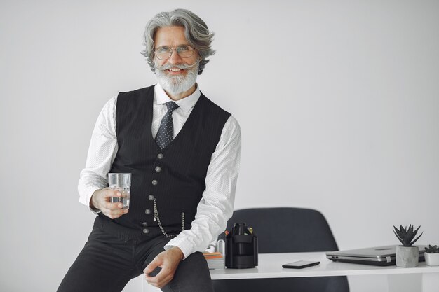 Close up portrait of grinning old-fashioned man.  Grandfather with glass of water.