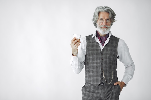 Close up portrait of grinning old-fashioned man.  Grandfather with a glass of whiskey.