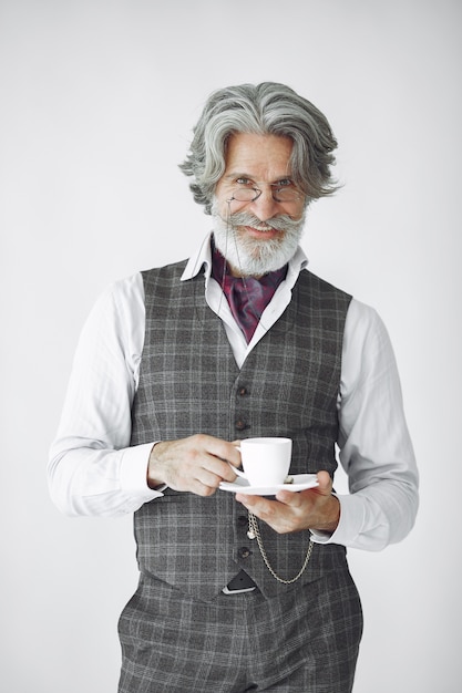 Free photo close up portrait of grinning old-fashioned man.  grandfather with a mug of tea.