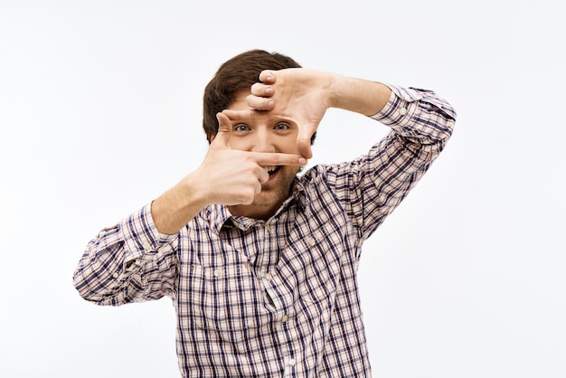 Free photo close-up portrait of handsome confident young blue-eyed dark-haired man wearing casual plaid shirt looking at front making frame with his hands