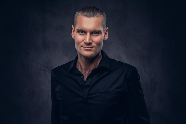 Free photo close-up, a portrait of a handsome man in black shirt poses against a dark background, standing in the studio.