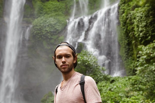 Free photo close up portrait of handsome man wearing baseball cap backwards relaxing outdoors