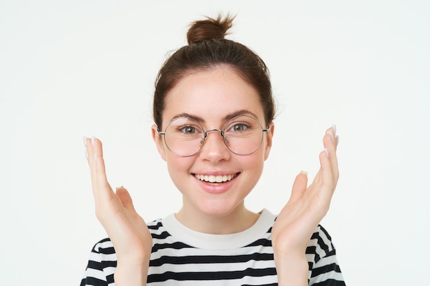 Close up portrait of happy beautiful young woman clapping looks pleased and smiling applause you