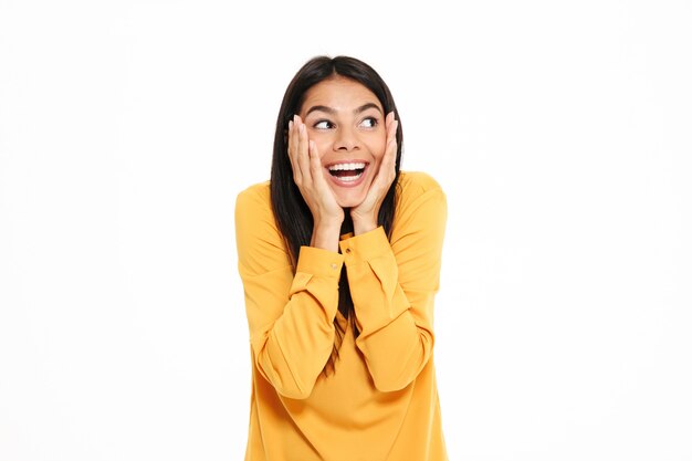 Close-up portrait of happy exited brunette woman holding her cheeks, looking aside