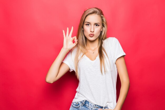 Close up portrait of happy girl gesturing ok sign isolated on red background
