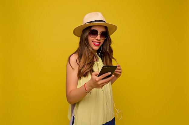 Close up portrait of happy girl is smiling over yellow floor Brownhaired woman in summer yellow dress and hat smiles broadly with her teeth Good mood concept leisure