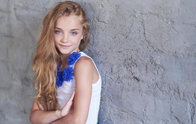 Close-up portrait of a happy little girl model with charming smile posing in a studio.