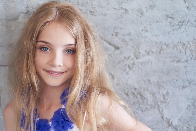 Ritratto del primo piano di un modello di bambina felice con un sorriso affascinante che posa in uno studio.