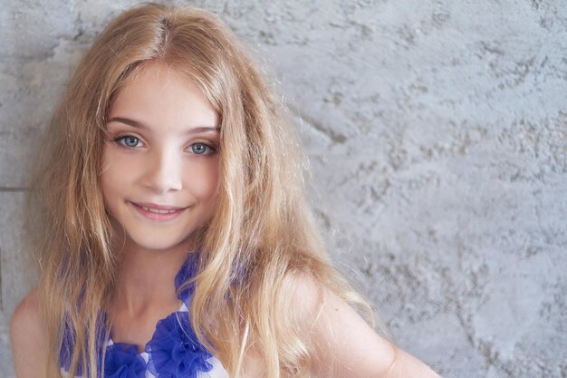 Close-up portrait of a happy little girl model with charming smile posing in a studio.