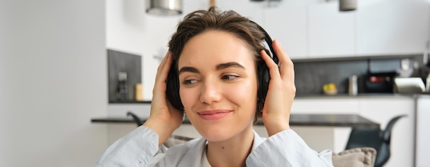 Foto gratuita ritratto ravvicinato di una ragazza felice e sorridente che indossa cuffie wireless, ascolta musica o si siede su un ebook