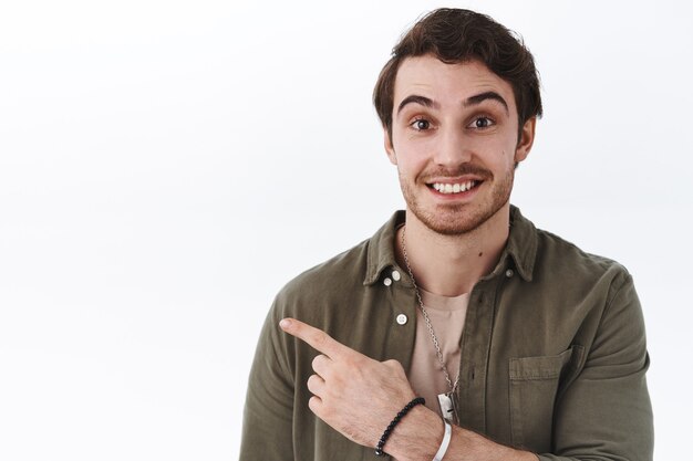 Close-up portrait happy smling man with beard pointing left at advertisement, suggest click banner