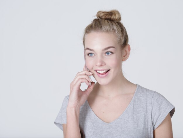 Close up portrait of a happy woman talking on the mobile phone on gray bacjground
