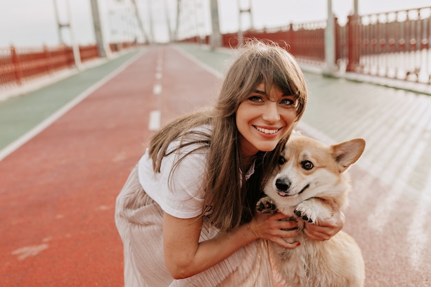 外で彼女の犬とポーズをとって長い髪の幸せな女性の肖像画をクローズアップ