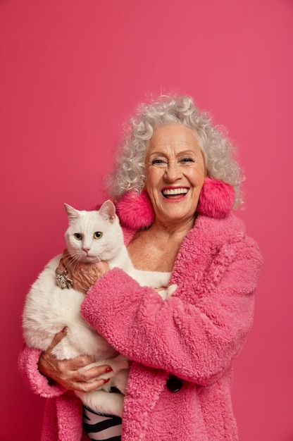 Close up portrait of happy wrinkled fashionable granny with beautiful cat