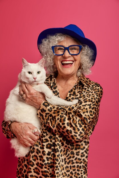 Close up portrait of happy wrinkled fashionable granny with beautiful cat