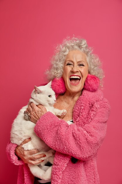 Крупным планом портрет счастливой морщинистой модной бабушки с красивой кошкой