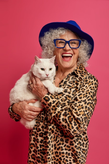 Close up portrait of happy wrinkled fashionable granny with beautiful cat