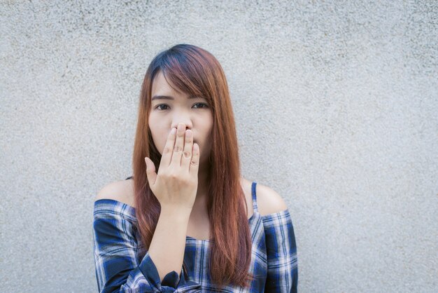 Close up portrait of happy young asian woman smiling and winking against gray  concrete wall. Vintage tone filter color style.