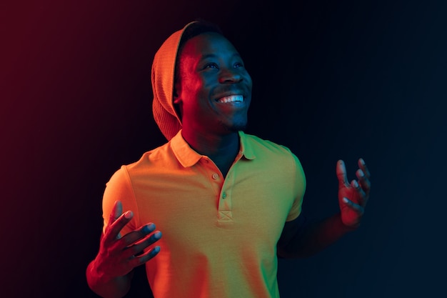 Крупным планом портрет счастливого молодого человека, улыбающегося против черной неоновой студии