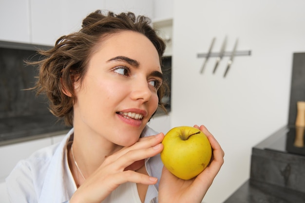 Free photo close up portrait of healthy beautiful young woman holding an apple smiling