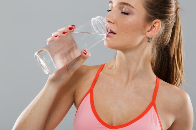 Close up portrait of healthy young sports girl drinking water