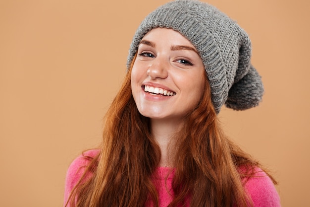 Крупным планом портрет радостного довольно рыжая девушка в зимней шапке