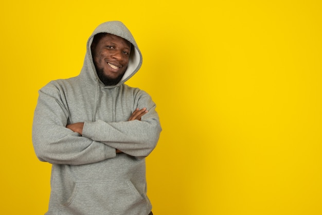 Close up portrait of laughing African American man standing with arms crossed , stands over yellow wall. 