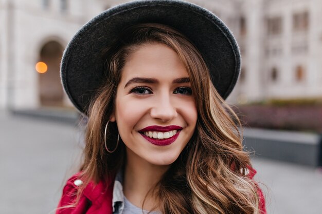 Close-up portrait of laughing blonde woman with red lips posing during walk around city