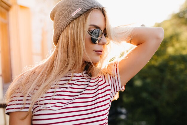 Close-up portrait of lightly-tanned blonde woman in trendy shining sunglasses