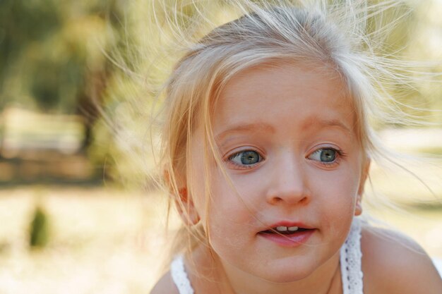 Close up portrait of a little blonde girl on a summer day