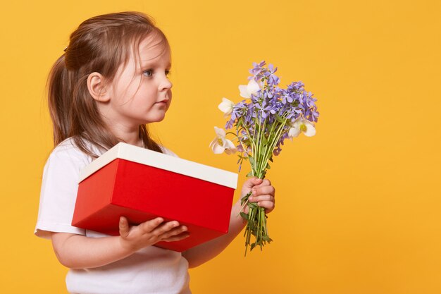 Close up portrait of little girl with red gift box and bouquet of blue florets