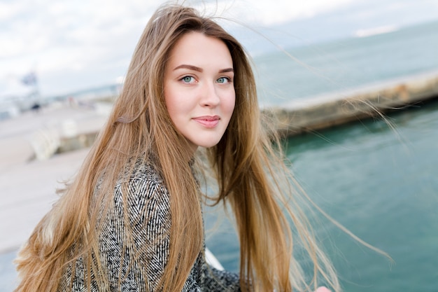 Close-up portrait of lovely charming woman with happy smile walks near the sea