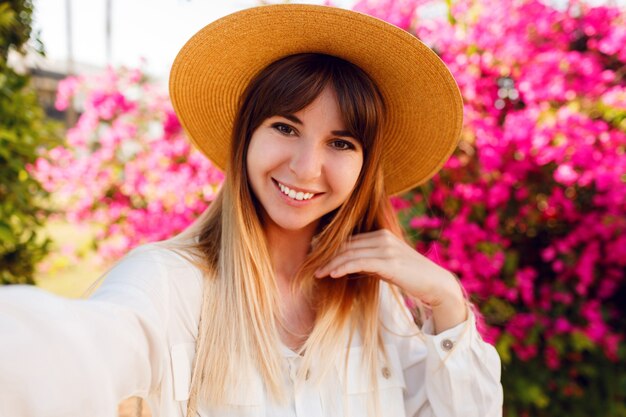 Close up portrait of lovely girl in trendy straw hat making selfie portrait