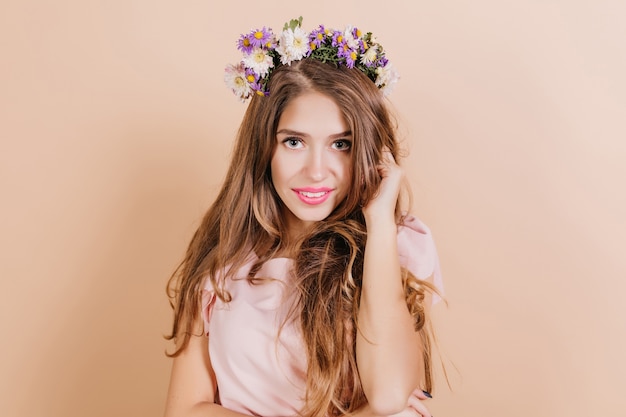 Close-up portrait of magnificent woman with long dark hair posing on light wall