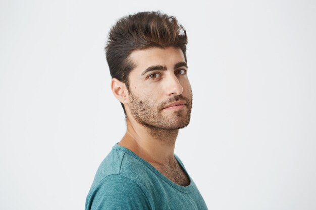 Close up portrait of mature caucasian guy, in blue tshirt, with good hairstyle and beard lightly smiling  in three-quarters. 3 4 close up portrait.