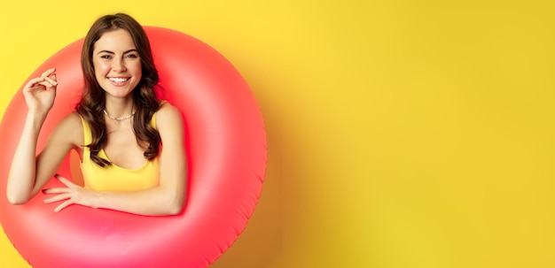 Бесплатное фото Крупным планом портрет красивой брюнетки модели внутри розового плавательного кольца пляжные аксессуары и