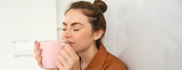 Бесплатное фото Близкий портрет красивой брюнетки с чашкой кофе, пьющей ароматический напиток из кружки