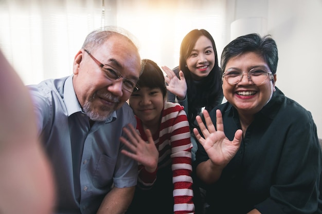 Крупный план портрета большой азиатской семьи дома делает селфи вместе, улыбающаяся маленькая девочка с молодой мамой и старшей бабушкой и дедушкой делают автопортрет на камеру
