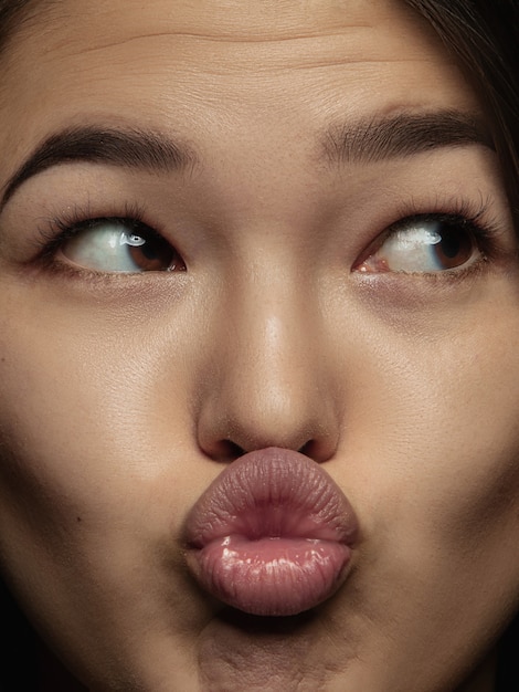 무료 사진 젊고 감정적 인 중국 여자의 초상화를 닫습니다. 잘 관리 된 피부와 밝은 표정으로 여성 모델의 매우 디테일 한 사진 촬영. 인간 감정의 개념. 키스 보내기.