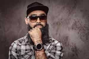 Free photo close-up portrait of a pensive bearded arabian male wearing checkered shirt sunglasses and cap.