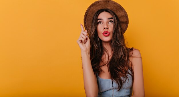 Close-up portrait of pensive dark-haired lady posing on bright space