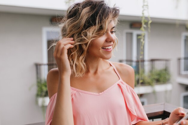 Close-up portrait of pensive woman touching her wavy hair. Outdoor photo of winsome caucasian girl posing