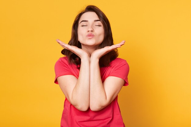 Close up portrait of pretty Caucasian woman makes kiss with lips