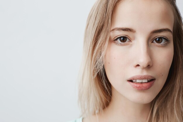 Close up portrait of pretty goodlooking european female with pure healthy skin looks pensively