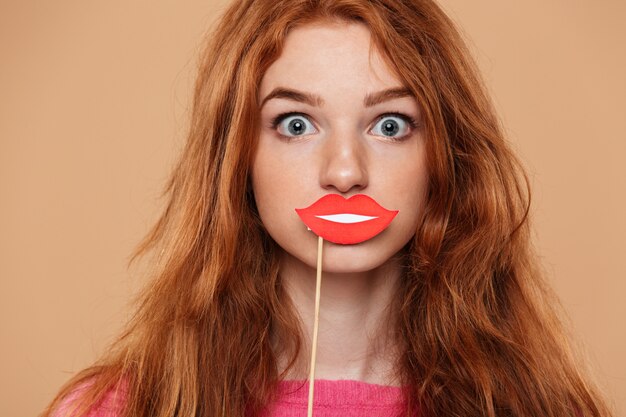 Close up portrait of a pretty young redhead girl with party paper mouth