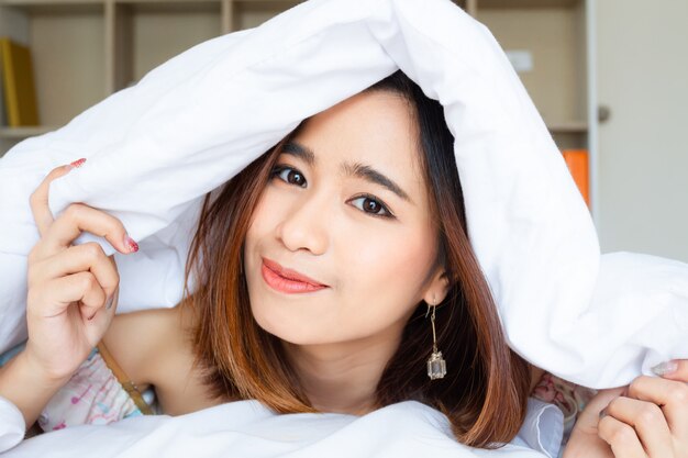 Close up portrait pretty young woman under white blanket 