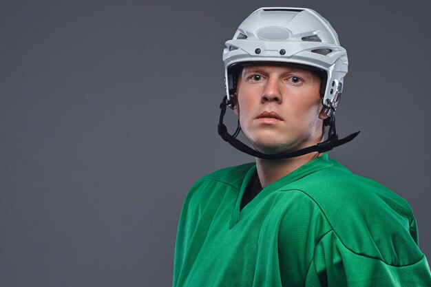 Close-up portrait of a professional hockey player in a protective sportswear and helmet. Isolated on a gray background.