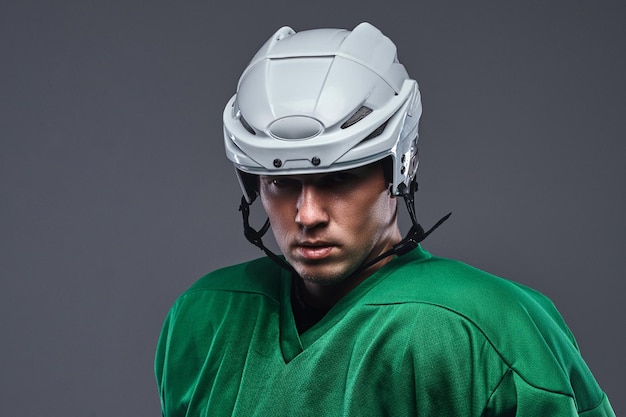 Foto gratuita ritratto ravvicinato di un giocatore di hockey professionista in un abbigliamento sportivo protettivo e casco. isolato su sfondo grigio.